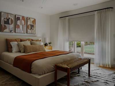 Blackout roller shades paired with drapes, on a patio door in a bedroom.